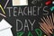 Flat lay composition with words TEACHER`S DAY and stationery on blackboard