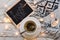 Flat lay with cup of green tea, blackboard with chalk written word `hygge`, yellow lights and woolen blanket on wooden backgroun