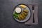 Flat lay dolma, parsley, saucepan with sour cream and lemon in a black plate on a dark table