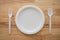 Flat lay of empty natural eco-friendly disposable utensils fork, spoon, dish plate made of fiber of bagasse and bamboo on wooden