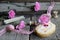 Flat lay food - dough biscuit roll, wooden bobbins, ribbon and pink carnations flowers on wooden background