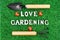 Flat-lay of garden hand tools and lettering LOVE GARDENING on grass