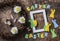 Flat lay handmade Easter decorations - wreath of vines with flowers, paper rabbits, ribbons, empty frame on a wooden background, t