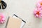 Flat lay home office desk. Female workspace with paper clipboard, pink dahlia flowers, woman accessories on stone background. Top