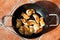 Flat lay image above traditional polish meal pirogi in the frying pan on the table. Delicious dough meal prepared on old