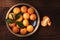 Flat lay image of a plate of fresh picked Mandarin Oranges in a rustic wood table with one peeled piece of fruit with warm side