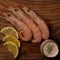 Flat lay image of unpeeled king prawns served with lemon slices and cocktail sauce as a starter or tapas