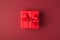 Flat lay layout close up view photo of small present box with bow and ribbon isolated maroon color background