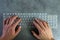 Flat lay of man hand typing on modern slim futuristic keyboard on desk