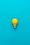 Flat lay minimalist photo of yellow painted bulb on turquoise blue backgound