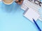 Flat lay of office blue desktop with blank notepad, pen and eyeglasses with stationery equipment and cactus, coffee cup.