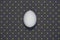Flat lay of one egg on dark polka background