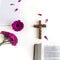 Flat lay: open Bible, wooden cross, open journal on white background and pink, purple, violette, red Gerbera flower with petals