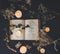 A flat lay of an open vintage poetry book on black table surface with white lit burning candles and dried baby`s breath flowers