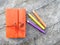 Flat lay - orange vintage notebook with color pencils on wooden table. Diary writing concept. Top view image