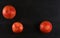 Flat lay photo - three whole red grapefruits on black slate board, space for text upper right