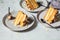 Flat lay of pieces of vegan cake on gray plates. Homemade carrot cake with white cream, caramel and nuts