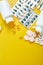 Flat lay of pills, fish oil, vitamins on yellow background