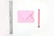 Flat lay: pink paper folded in the shape of envelop, pencil, silver ruler. Making a postcard in an envelope for Valentine`s Day.