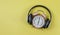 Flat lay of pink vintage alarm clock show 6 o`clock cover with headphones on yellow background ,time to listen to music concept