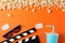 Flat lay. Popcorn, clapperboard, 3d glasses, drink and tickets on orange background