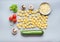 Flat lay of Raw tortellini pasta with ingredients for tasty vegetarian cooking on gray background , top view . Italian cuisine