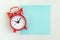 Flat lay of red alarm clock with blank sticky note for message on white background with copy space using as time, deadline, stop