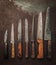 Flat lay set of carbon steel knives on old rusty metallic background