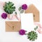 Flat lay shot of letter and eco paper envelope on white background. Wedding invitation cards or love letter with flowers