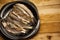 Flat lay small fresh fish chub on a black plate on the wooden box