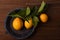 Flat lay still life of a group of fresh picked lemons attached to leaves and stem on a round blue plate