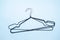 Flat lay of stock metal black thin clothes hangers isolated on blue background. Store concept, sale, design, empty hanger.