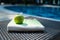 A flat lay summer accessories close-up of a white and green Turkish peshtemal / towel and green apple on a rattan lounger.