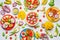 Flat lay of summer various colorful sliced tropical fruits and berries in plates and bowls on white background