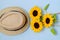 Flat lay with sunglasses, straw boater hat and bright big yellow sunflower on blue background. Travel summer concept. Copy space