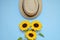 Flat lay with sunglasses, straw boater hat and bright big yellow sunflower on blue background. Travel summer concept. Copy space