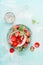 Flat lay with Sweet sliced Strawberries in bowls with icing sugar on light blue background