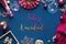 Flat lay, text Feliz Navidad means Merry Christmas in Spanish. Classic blue linen table with pink and red Xmas decorations
