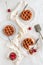 Flat lay of three cherry pies and fresh cherries on white plates  a white background and a serving utensil