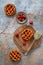 Flat lay of three cherry pies on a textured blue and rustic background  wooden board and serving utensil