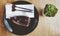 Flat lay or top view of blueberry cheesecake with forks and white napkin on black dish or plate with green cactus on brown wooden