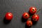 Flat lay, top view. Close up. A small sprig of bright juicy cherry tomatoes. Nearby is one tomato. Black background. Copy space