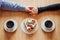 Flat lay, top view of man and woman holding hands while drinking coffee with cream cake