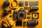 Flat lay or top view of photographer workplace with dslr camera, lens, pen tablet and camera accessories with yellow background.