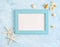 Flat lay top view Summer vacation mockup: photo frame, seashells and white starfish on blue background. Travel, beach concept