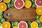 Flat lay. Top view. Wooden board in the center with sliced kiwi, orange, grapefruit and mandarin on light background. ,