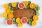 Flat lay. Top view. Wooden board in the center with sliced kiwi, orange, grapefruit and mandarin on light background.