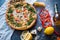 Flat lay with traditional Italian with shrimp, mozzarella and arugula on dark blue stone table and various ingredients