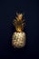 Flat lay tropical gold pineapples on a dark background