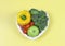 Flat lay of vegetables  capsicum, broccoli and tomatoes and apple  in heart shape plate  on yellow background  with copy space,